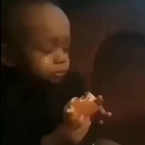A baby savoring a Popeyes chicken sandwich in a restaurant, embodying the delightful moments featured in Popeyes memes.